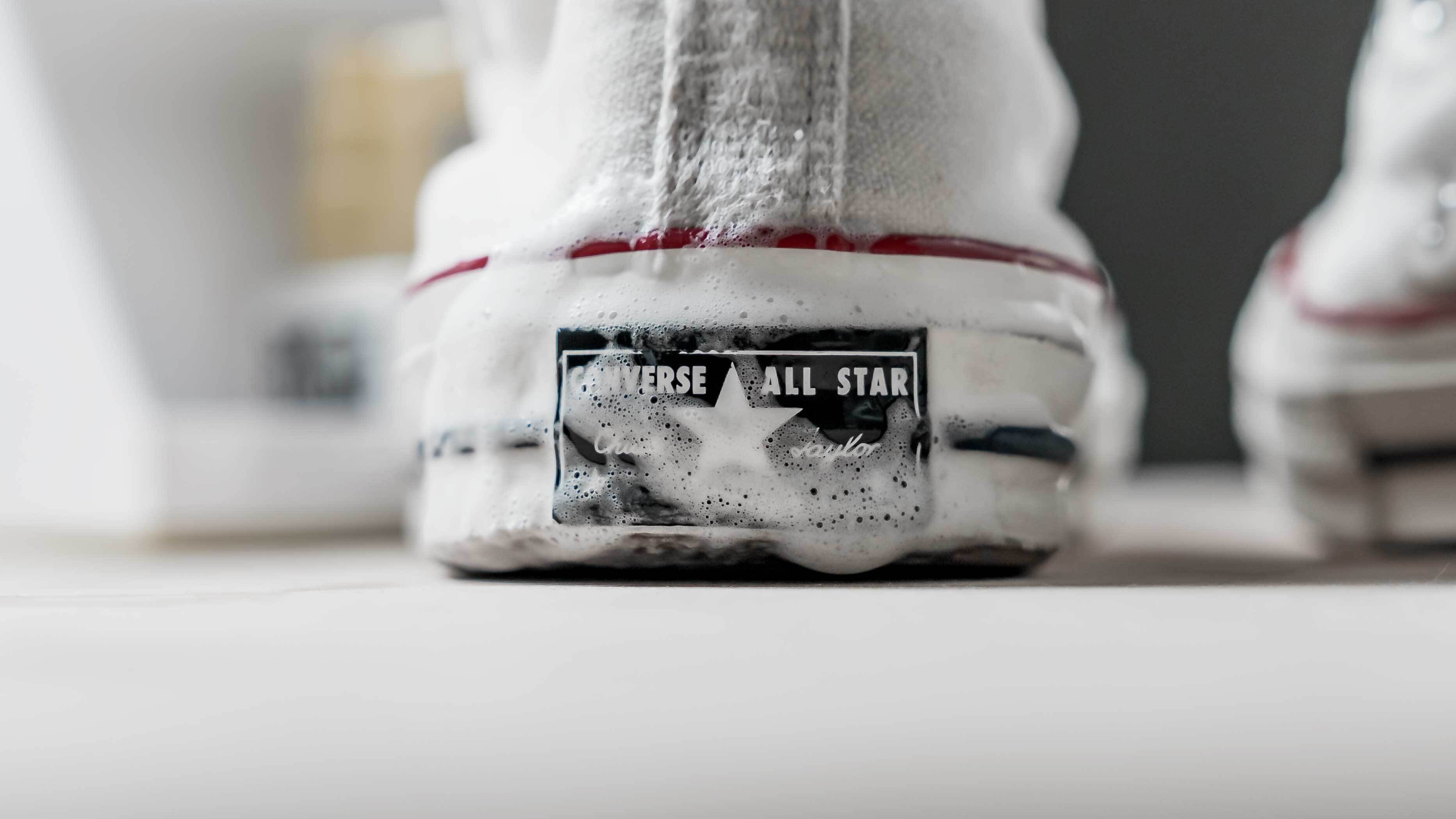 Närbild på Converse All Star med rengöringsskum – vit canvas-sneaker under rengöring